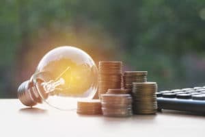Energy saving light bulb with stacks of coins and calculator for financial, accounting and saving concept.